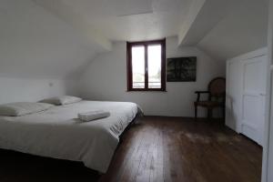 een witte slaapkamer met een bed en een raam bij Maison dans le bourg, 6-8 couchages avec piscine in Groléjac