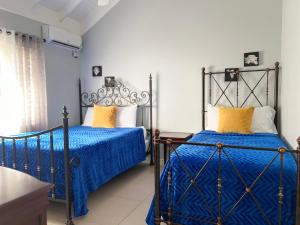 two beds in a bedroom with blue sheets and yellow pillows at Isle Be Back Villa in Priory