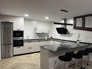 a kitchen with white cabinets and a black counter top at MIRAGREDOS CASA RURAL in Mombeltrán