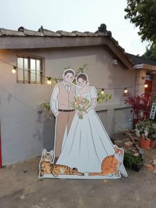 a painting of a bride and groom in front of a house at Fun Kaohsiung Backpacker Hostel in Kaohsiung
