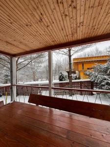 une terrasse couverte avec un banc en bois dans la neige dans l'établissement Wood House Valiug, à Văliug
