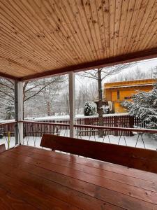 a covered porch with a wooden bench in the snow at Wood House Valiug in Văliug +35 photos