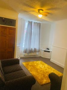 a living room with a couch and a yellow rug at Portable Single room in Bury