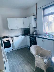 a kitchen with white cabinets and a chair and a sink at Portable Single room in Bury