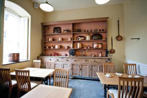 Plas Nanteos Mansion في آبريستويث: غرفة طعام مع طاولات ورف من الفخار