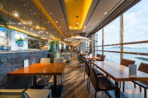 a restaurant with tables and chairs and large windows at Inchon sky and sea ocean view hotel in Incheon