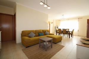 sala de estar con sofá amarillo y mesa en Bela Vista Family Flat near Ferragudo beach, en Parchal