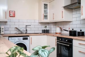 eine Küche mit weißen Schränken und einem Geschirrspüler in der Unterkunft Central Apartment in Belfast City Centre in Belfast