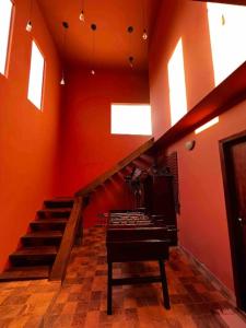 a staircase with a piano in a room with red walls at Casa de campo! Lugar de paz! Próxima as praias não oferecemos roupa de cama e banho in São Pedro da Aldeia