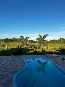 a blue swimming pool with a view of a field at Casa de campo! Lugar de paz! Próxima as praias não oferecemos roupa de cama e banho in São Pedro da Aldeia