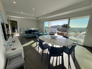 Villa Serena vista mare في لاكونا: غرفة معيشة مع طاولة وكراسي بيضاء