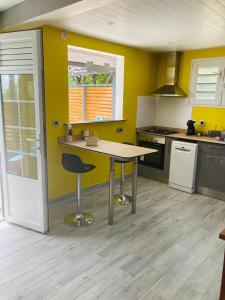 a kitchen with yellow walls and a table and a chair at Labellapose in Le Diamant