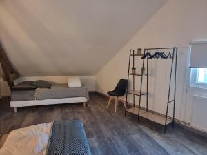 ein Schlafzimmer mit einem Bett und einem Stuhl auf einem Dachboden in der Unterkunft Échappée belle en baie de Somme in Saint-Quentin-Lamotte-Croix-au-Bailly
