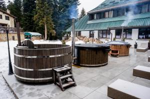 een houten bad en twee vuilnisbakken in de sneeuw bij Breza Hotel Borovets in Borovets