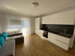 una cucina con armadi bianchi e un divano in camera di Apartament NALA a Mediaş