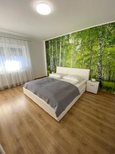1 dormitorio con 1 cama con un mural de árboles en Apartament NALA, en Mediaş