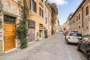 eine Kopfsteinpflasterstraße mit geparkten Autos und Gebäuden in der Unterkunft Trastevere Stylish in Rom