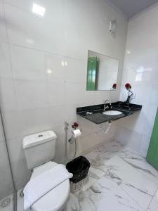 a white bathroom with a toilet and a sink at Pousada Sesmaria in Lavras Novas