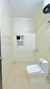 a white bathroom with a toilet and a window at Hotel Relax In - Noida Sector 18 in Noida