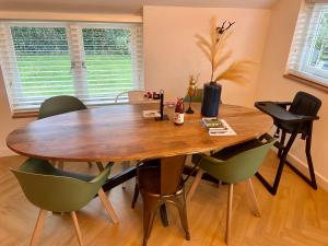 a dining room table with green chairs around it at Luxe villa met geweldige omheinde tuin aan Veluwse bosrand in Ermelo