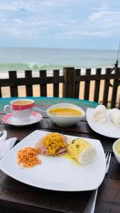 a table with plates of food and bowls of soup at Hakuna Matara Beach Bungalows in Matara
