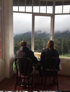 Un uomo e una donna seduti a un tavolo che guardano fuori dalla finestra di King's Lodge a Nuwara Eliya