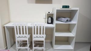 Elle comprend un bureau blanc avec deux chaises et une cafetière. dans l'établissement España Confort 2, à Ciudad del Este