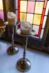 dos velas en un puesto frente a una vidriera en Kirkby Stephen Hostel, en Kirkby Stephen