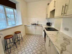 a kitchen with white cabinets and two bar stools at Central Brighton Pavilion Pad. in Brighton & Hove