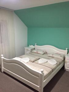 a white bed in a room with a blue wall at Motel Albatros in Kosovo Polje