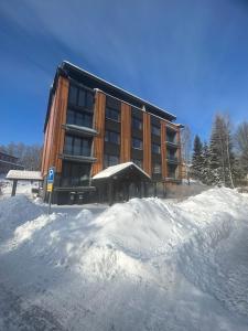 um grande edifício com neve em frente em Apartmán ROKY 6 em Rokytnice nad Jizerou