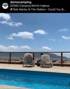 a man sitting in two chairs next to a swimming pool at DOMO CAMPING in Bahia Inglesa