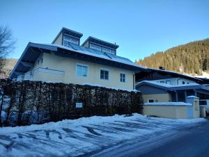 a white house with a fence in the snow at Appartement Lockei in Eben im Pongau