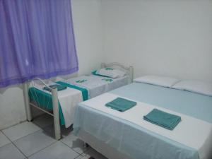2 Betten in einem Zimmer mit lila Vorhängen in der Unterkunft Chacara Cabana dos Lagos in Riachão