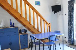 a blue table and chairs in a room with a staircase at Maisons du lac in Le Barcarès