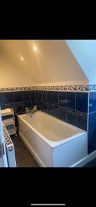 een wit bad in een badkamer met blauwe tegels bij Meadow View in Hurst