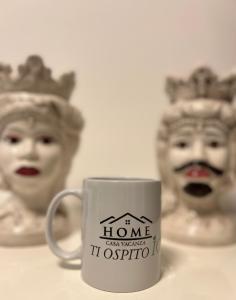 a white coffee mug with a figurine of a statue at Casa Vacanza Ti Ospito io in Catania