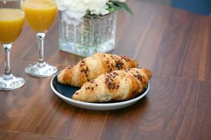 two rolls on a plate next to two glasses of orange juice at Serene Haven 4-Bed House in Norwich in Norwich