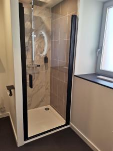 La salle de bains est pourvue d'une douche avec une porte en verre. dans l'établissement Les Bras de Morphée, à Avize