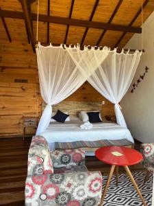 a bedroom with a bed with curtains and a couch at Pousada Sesmaria in Lavras Novas