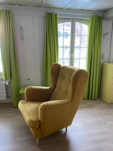 a living room with a chair and green curtains at B&B tannen124 in Oberburg