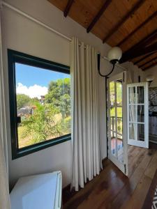 a room with a large window with a view of a yard at Pousada Sesmaria in Lavras Novas