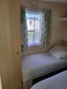 a small bedroom with a bed and a window at Chapel's cozy caravan in Chapel Saint Leonards