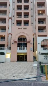 a large pink building with a large entrance at Adar Homes 2 - شقة غرفتين نوم مطلة على البحر in King Abdullah Economic City