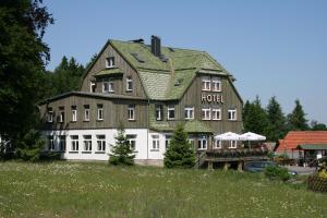 a large building with a hotel on top of a field at waldhotel AUSZEIT mit Restaurant & Café in Tanne
