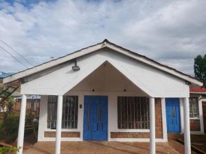 a white and blue building with blue doors at A Lovely smart family guest house in Kisii