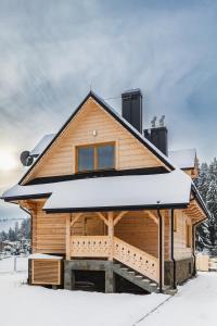 Cabaña de madera con nieve en el suelo en Ł.owca relaksu, en Niedzica