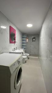 El baño incluye lavadora, lavamanos y aseo. en Ardjon House en Berat
