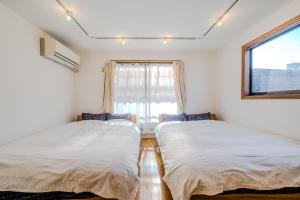 two beds in a room with a window at Shinjuku / 5 min walk from station ※ projector in Tokyo