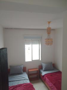 a bedroom with two beds and a chandelier at Appartement in Casablanca close to the beach in Casablanca